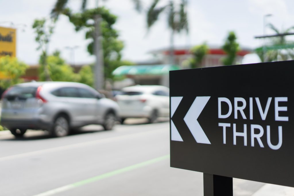 Sign pointing to drive thru with cars in background